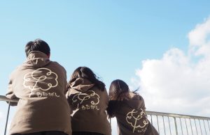 わたがしパーカーを着た3人が青空を見上げている様子